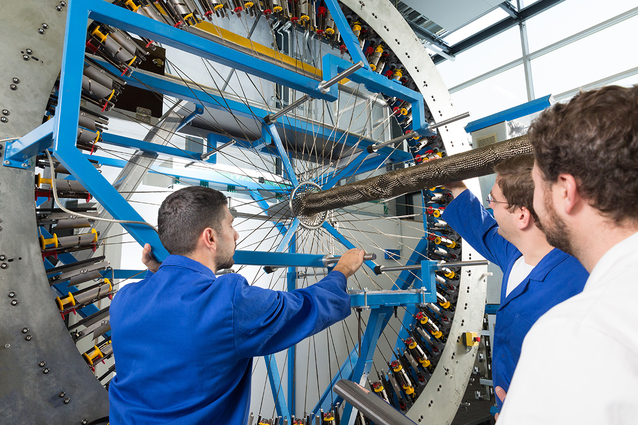 Drei Männer stehen vor einem großen blauen Gerät und betrachten es
