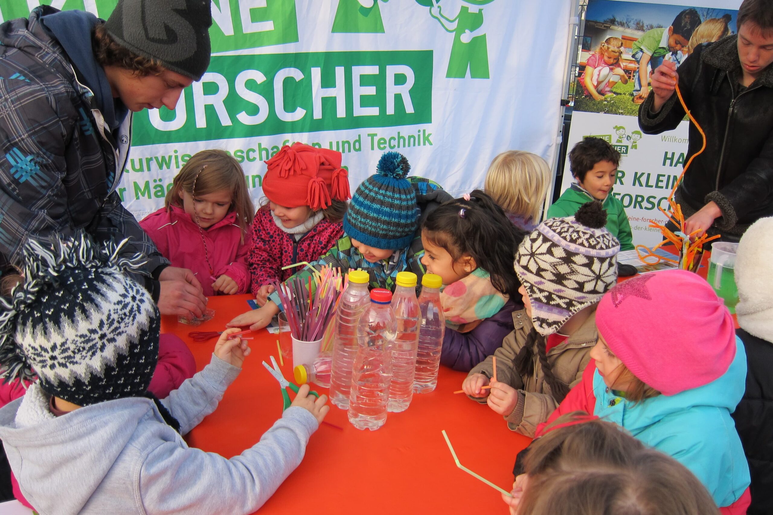 Children sit around a table and do handicrafts